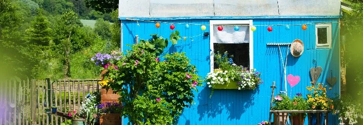 Blau gestrichenes Gartenhaus mit vielen Blumen